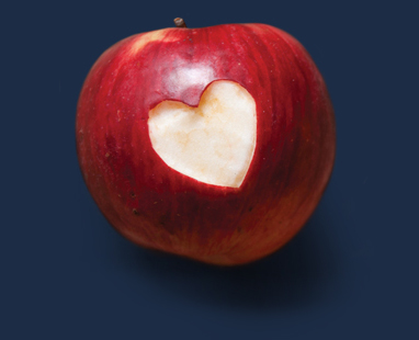 Red apple with a heart shaped hole in the skin.